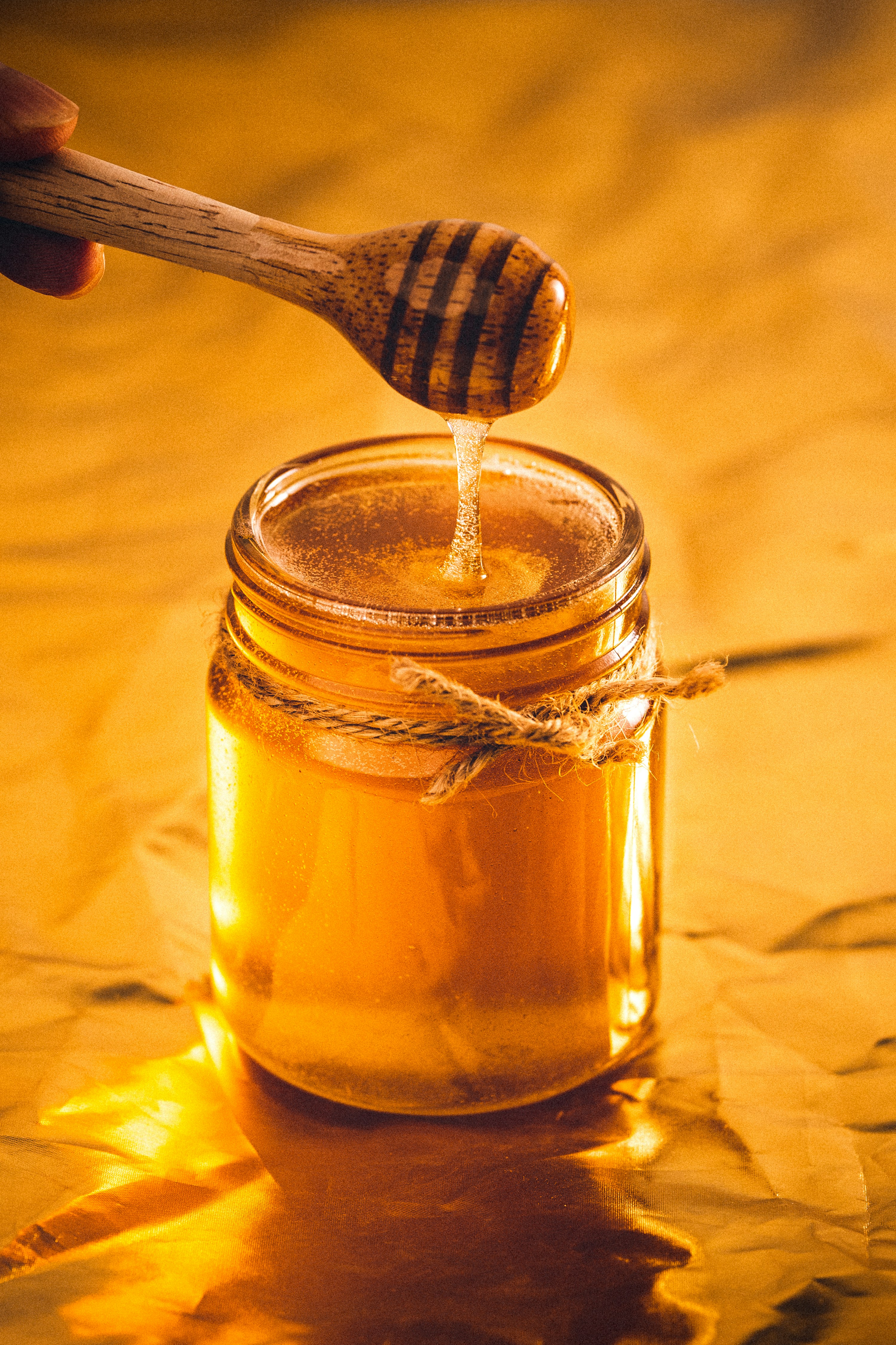 Miel doré versé dans un pot en verre